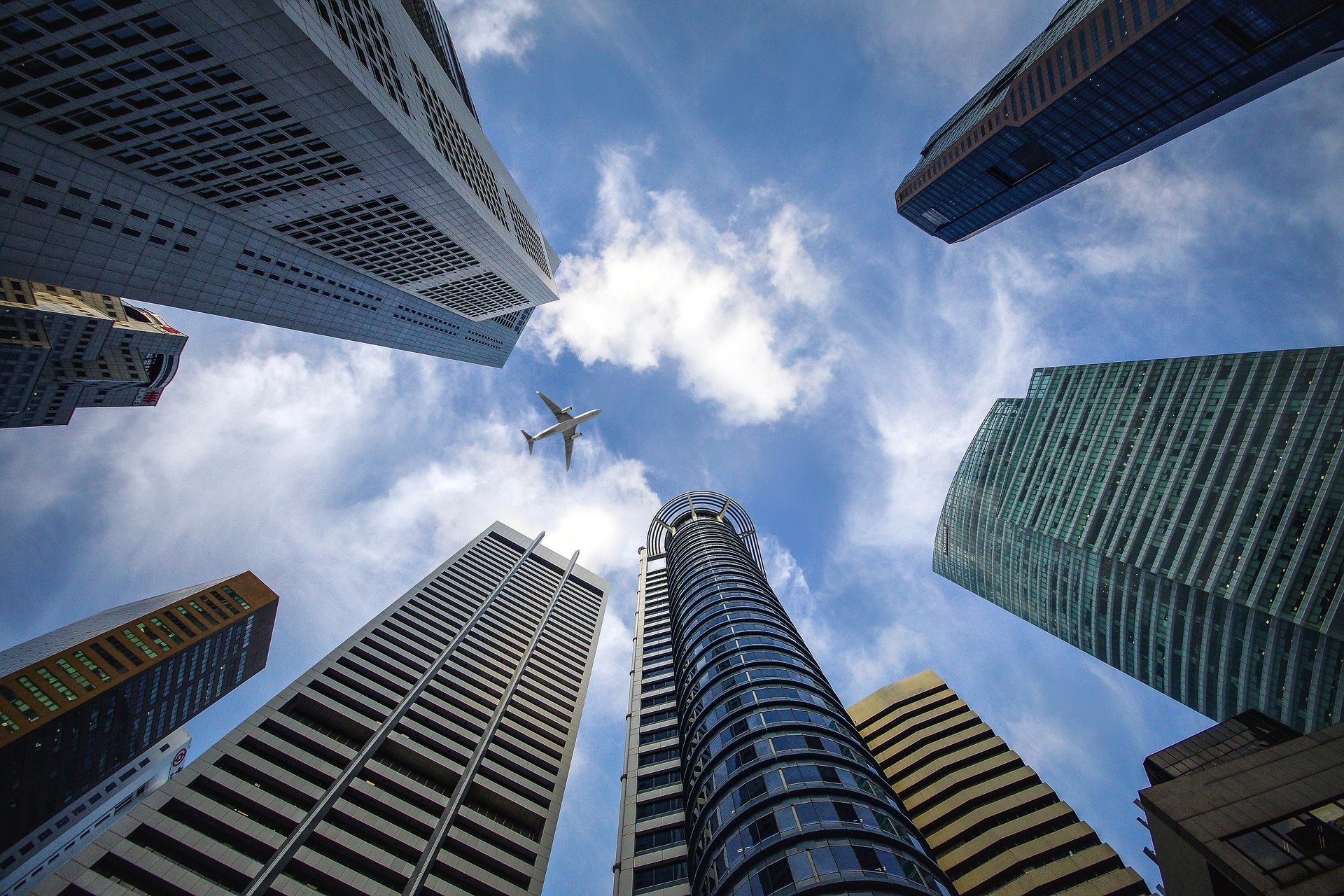 perspectiva desde el suelo de una ciudad con edificios y va volando un avión